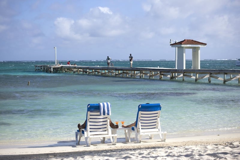 People in our beachfront lounge chairs enjoying a drink in front of our hotel in San Pedro, after enjoying the top things to do in Belize like fishing